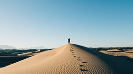 person walking on sand dune